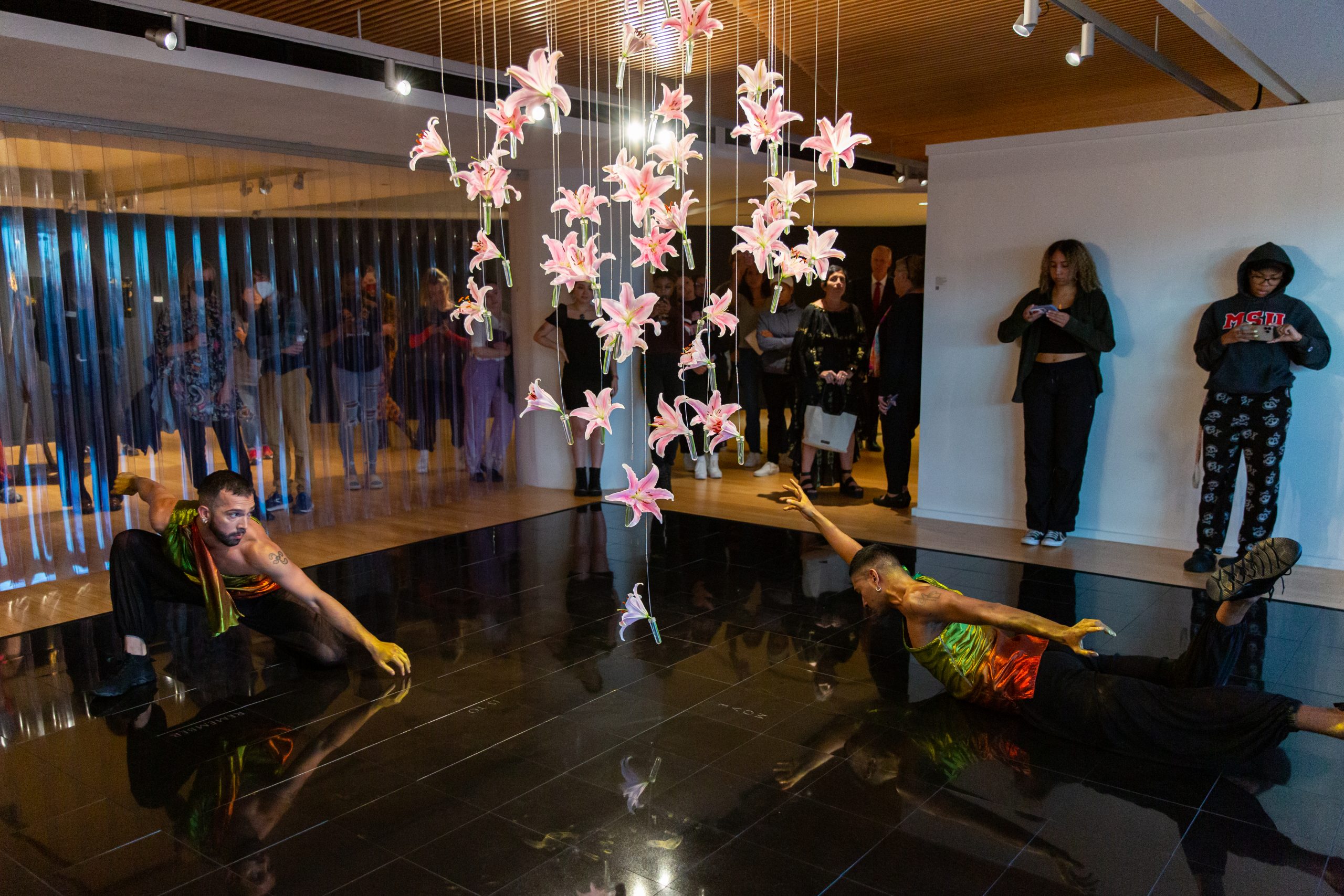 Dancers perform on an artwork in the Segal Gallery as visitors stand by watching.