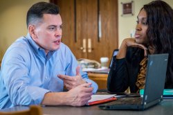Two students converse over notes in a collaborative workspace