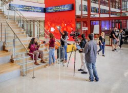 SCM students filming on lobby stairs