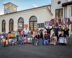 Students Holding Photojournalism Project Photos outside of School of Communication Building
