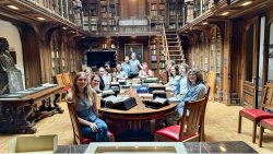 student Emily Walker sits at a large table with other workshop participants in a special library archives room