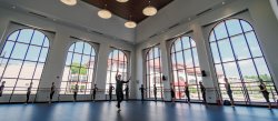 Dancers practicing in front of large windows in large dance studio