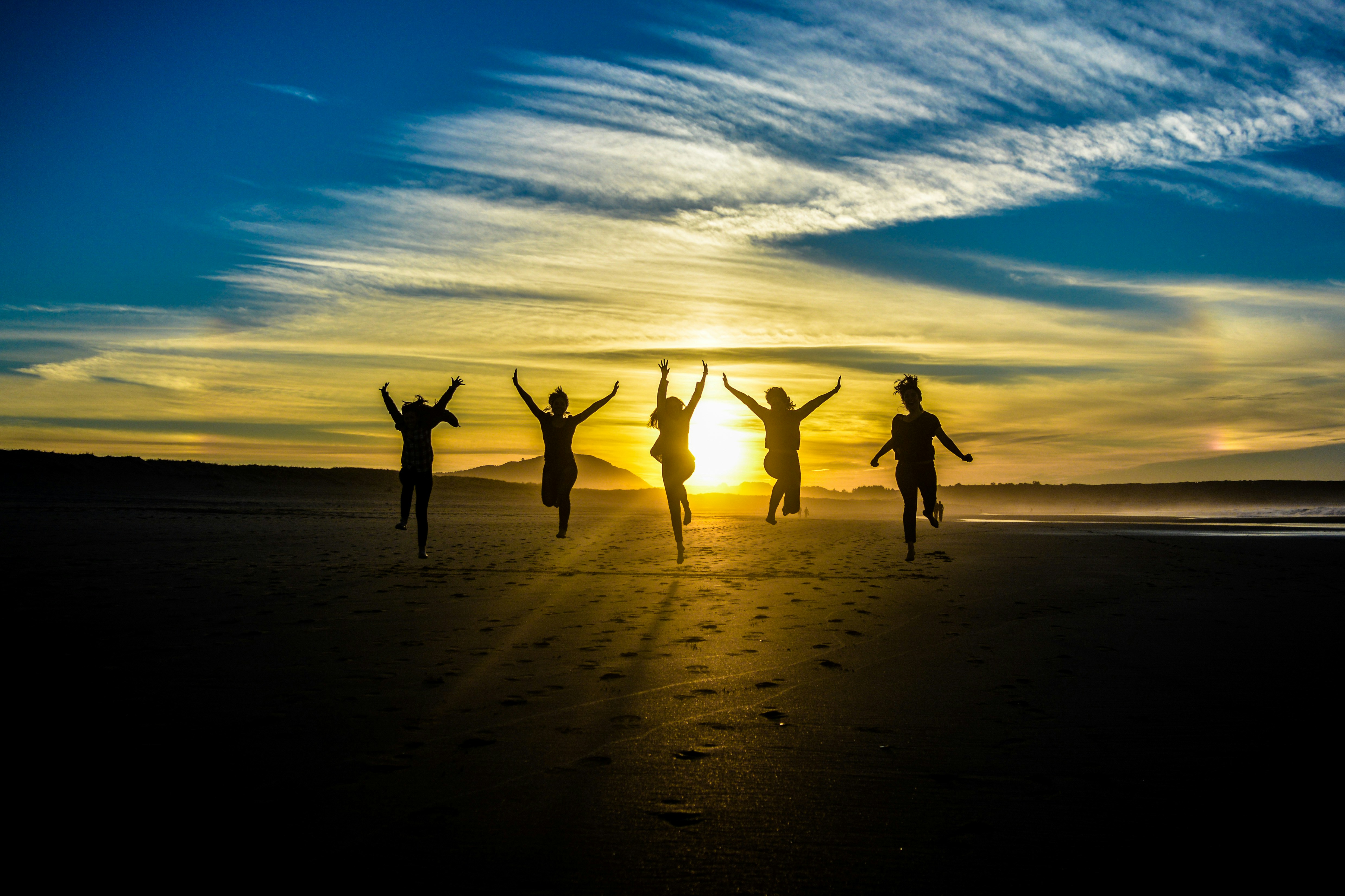 People jumping in the air with sun setting in the background