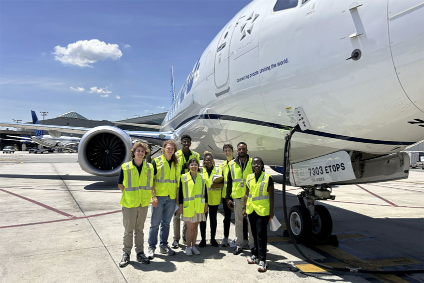 Green Team group by airplane while it's being refueled