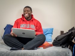 Student in dorm room using laptop