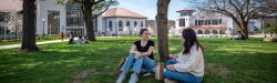 Two female students sitting on the lawn outside of Cole Hall