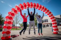 Alumni jumping under balloon arch