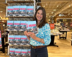 Stacy Rubis poses in front of a display of her new novel at a bookstore.