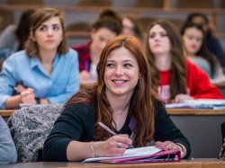 photo of female student smiling and taking notes in class