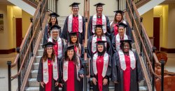 Group of 11 adult students in regalia taking a group photo at a graduation senior send-off celebration.