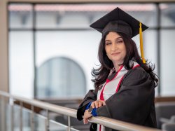 Female student proudly wears undergraduate black regalia ahead of her graduation.