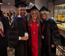 professor Jeffrey Gonzalez, Paloma Lupino and professor Laura Nicosia pose for a photo in commencement regalia