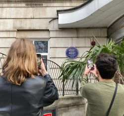 students using phones to take photo of plaque on wall