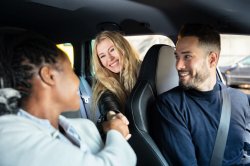 Photo of the interior of a car with carpool members shaking hands and smiling.