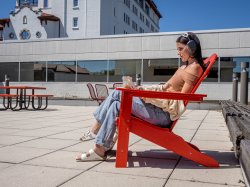 Student sitting in lounge chair outside on laptop.