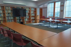 conference room with long tables, chairs and a monitor