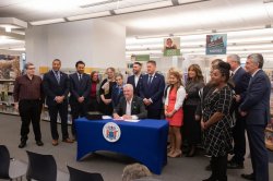 library staff and government representatives standing around NJ governor murphy signing a new law