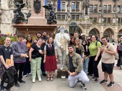 a group of students stands together for a photo next to a statue in Munich