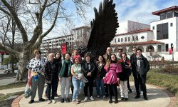 group of students stand together for photo in front of Red Hawk Statue