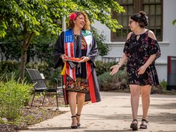 A graduate and her college-age daughter walk on campus.