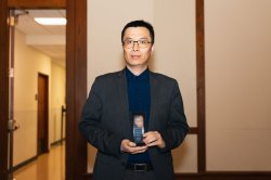 Weitian Wang holds an award.