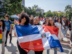 Students participating in a processional, proudly holding the flags of their respective countries during Montclair State University's flag-raising ceremony for Hispanic Heritage Month.