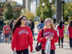 Two students in red sweatshirts walk on campus.