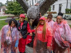 People in front of red hawk statue