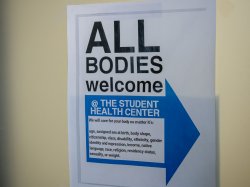 A sign on the door to the Student Health Center, with text detailing the All Bodies Welcome policy