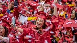 graduate holds cell phone to take selfie amid a flurry of confetti