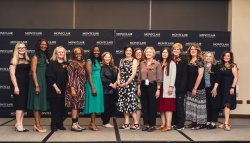 School of Nursing faculty standing in front of a step and repeat banner.