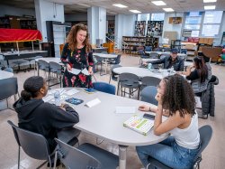 Teacher speaking to 2 adult students at a table