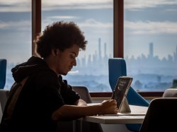 Montclair student studying on laptop with NYC skyline in background