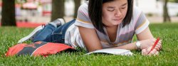 Photo of student in grass studying