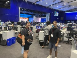 Two students standing and smiling in a TV studio.