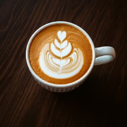 An overhead image of a coffee cup with pumpkin-colored liquid in a white coffee mug.