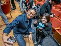 Josh Dela Cruz takes a selfie with a Montclair student holding a stuffed animal.