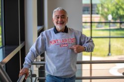 Adult degree completion student proudly wears a Montclair State University alumni crewneck sweatshirt on campus.