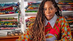 Bisa Butler poses for photo in front of her collection of printed fabrics