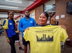 Student poses for camera holding National Day of Service t-shirt