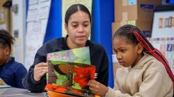 Student teacher sits with young child and reads a storybook with her
