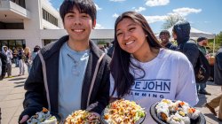 Two students at food festival holding plates of samples
