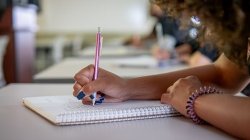 close-up photo of a hand holding a pen writing in a notebook
