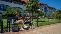 Two students sitting on bench outside Schmidt Hall