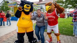 staff member poses with Bloomfield bear mascot and Rocky the red hawk