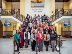 Large group of women pose on foyer stairs in Feliciano School of Business