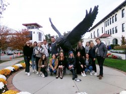 group of students pose around hawk statue on Montclair State University campus
