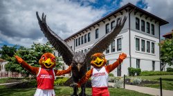 Rocky and Roxy pose with the hawk statue on campus