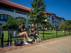 Two students sitting on a bench and talking.