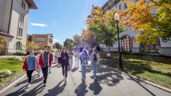 Students walking down a walkway surrounded by buildings led by a campus tour guide